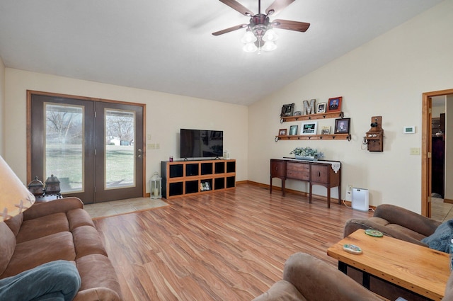 living room with lofted ceiling, light wood-style floors, baseboards, and a ceiling fan