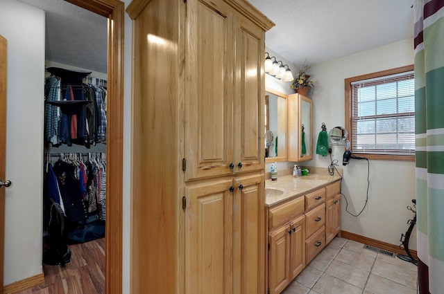 full bathroom featuring double vanity, visible vents, a sink, a textured ceiling, and tile patterned flooring