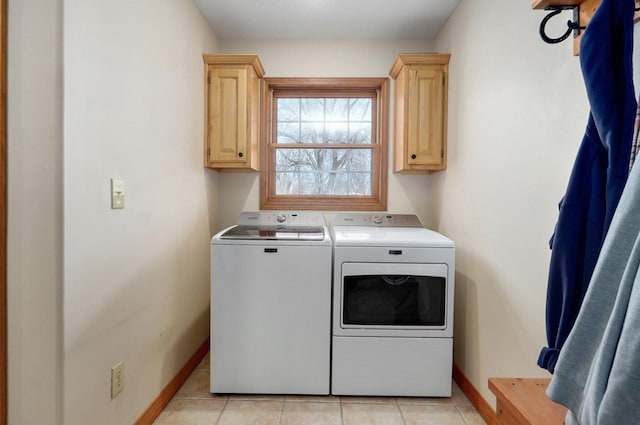 clothes washing area with light tile patterned floors, washing machine and clothes dryer, cabinet space, and baseboards