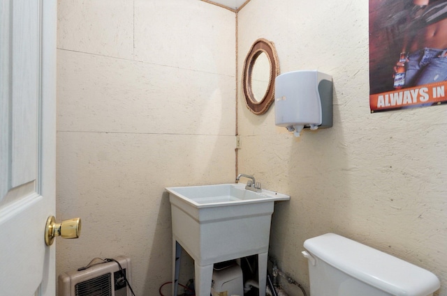 half bathroom featuring a textured wall, vanity, toilet, and heating unit