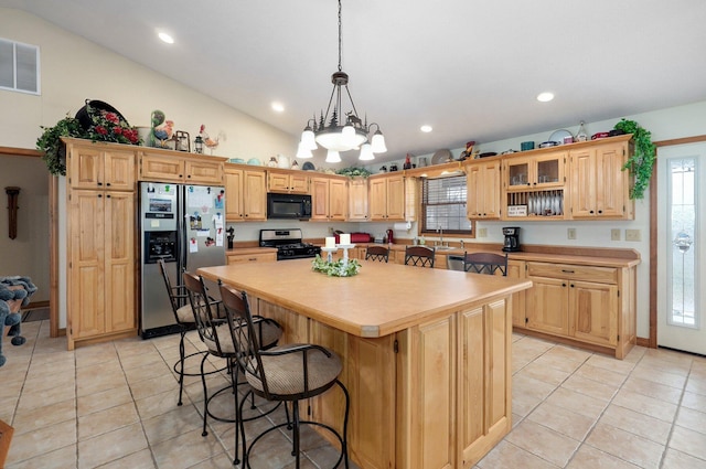 kitchen with light brown cabinets, visible vents, vaulted ceiling, appliances with stainless steel finishes, and a center island