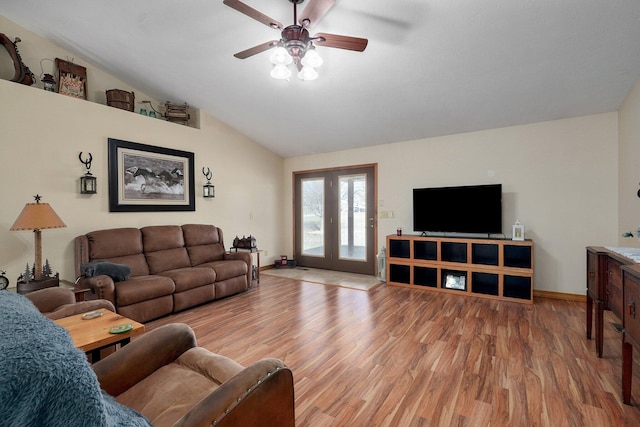 living room featuring a ceiling fan, baseboards, vaulted ceiling, and light wood finished floors