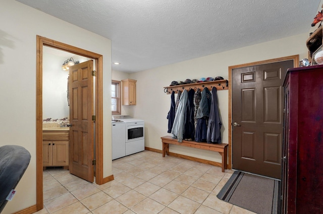 interior space with light tile patterned floors, a textured ceiling, washing machine and dryer, and cabinet space