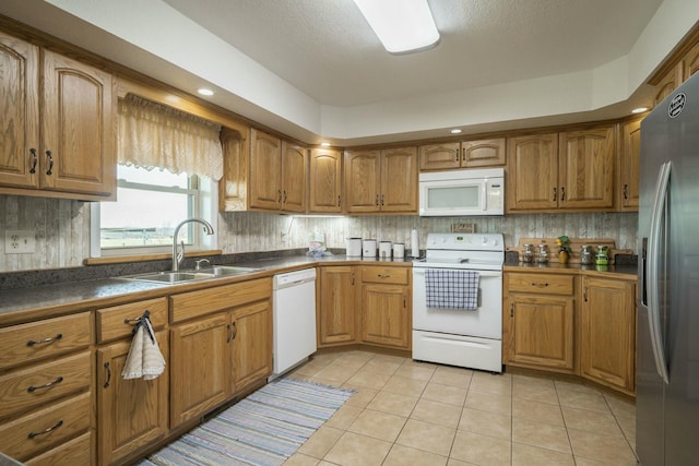 kitchen with white appliances, brown cabinets, and a sink