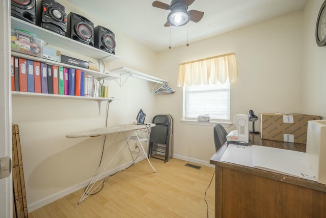 home office featuring a ceiling fan, wood finished floors, visible vents, and baseboards