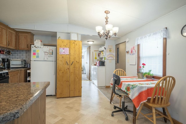 kitchen featuring lofted ceiling, a toaster, freestanding refrigerator, brown cabinetry, and dark countertops