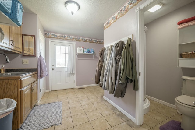 bathroom featuring tile patterned flooring, baseboards, a textured ceiling, and toilet