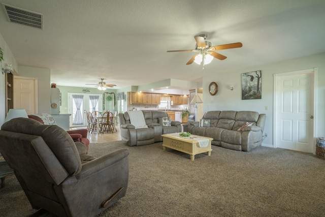 living room featuring carpet floors, visible vents, and a ceiling fan