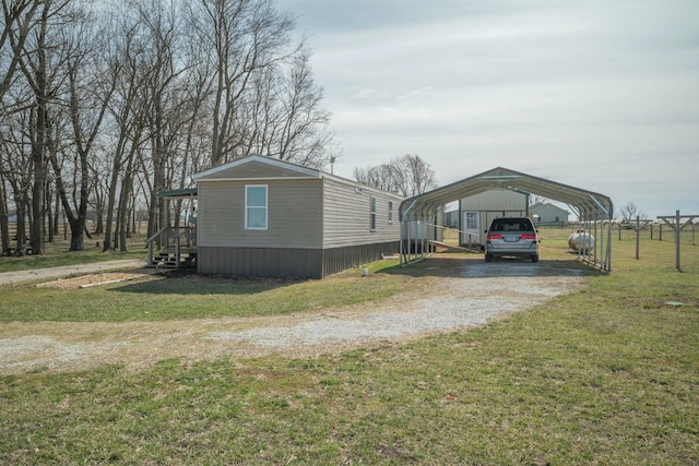 view of side of home with a detached carport, a yard, and driveway