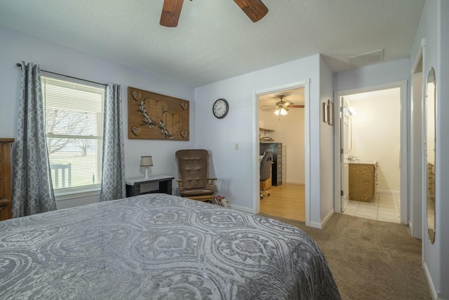 carpeted bedroom featuring a textured ceiling, ensuite bath, visible vents, and baseboards