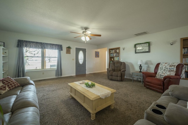 carpeted living area with a ceiling fan, visible vents, a textured ceiling, and baseboards