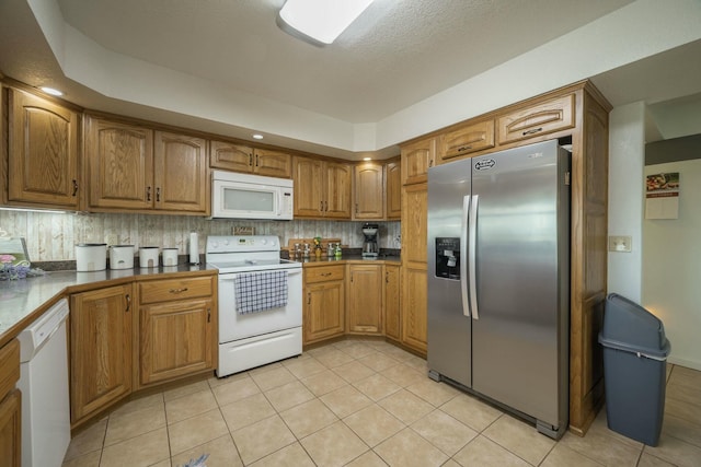 kitchen featuring white appliances, brown cabinetry, backsplash, and light tile patterned flooring