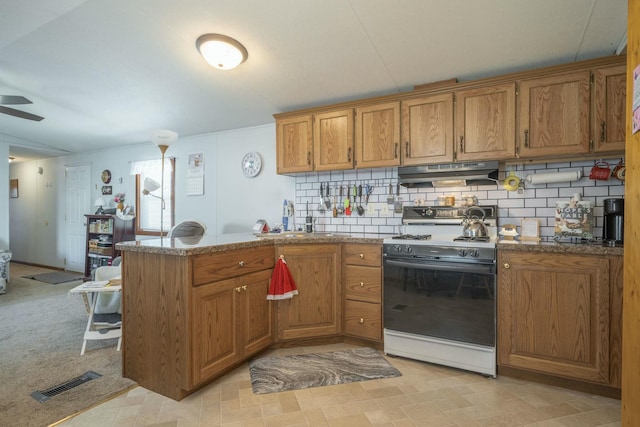 kitchen featuring a peninsula, electric range, brown cabinetry, and under cabinet range hood