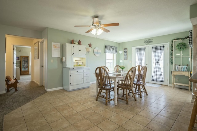 dining area with french doors, light colored carpet, ceiling fan, and light tile patterned floors