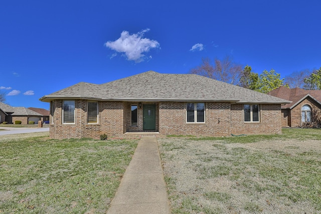 single story home featuring brick siding, a shingled roof, and a front yard