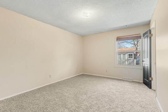 carpeted empty room with visible vents, a textured ceiling, and baseboards