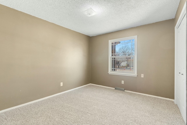 carpeted empty room featuring a textured ceiling, visible vents, and baseboards