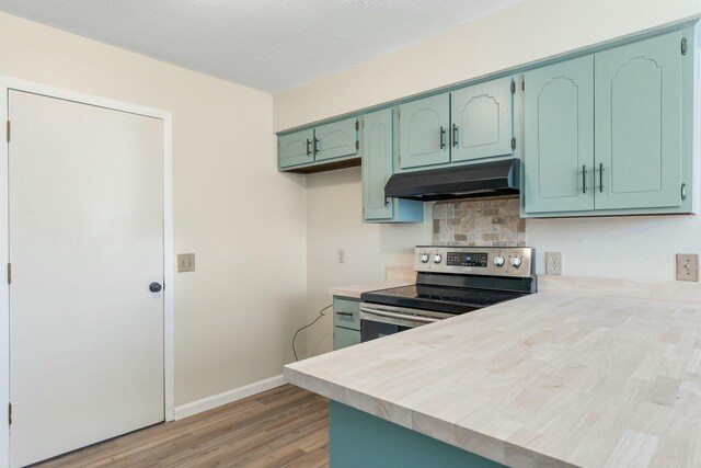 kitchen featuring stainless steel range with electric stovetop, light countertops, under cabinet range hood, and a peninsula