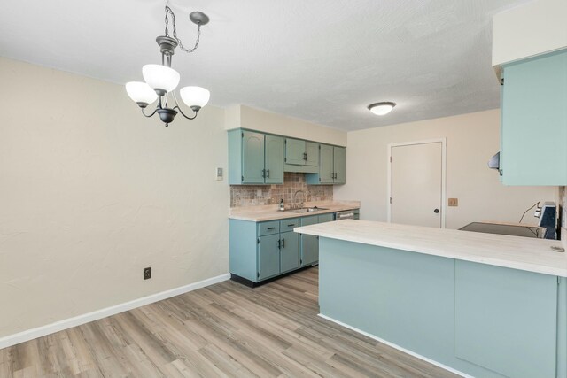 kitchen featuring tasteful backsplash, light countertops, a sink, a peninsula, and baseboards