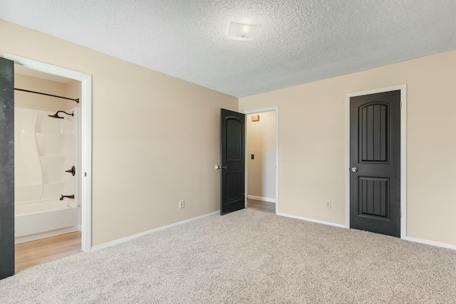 unfurnished bedroom featuring a textured ceiling, carpet flooring, and baseboards