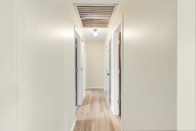 corridor featuring light wood-style floors, baseboards, and visible vents
