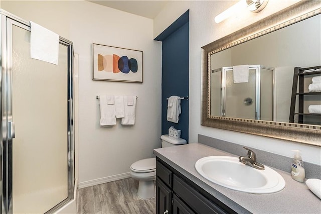 full bathroom featuring baseboards, toilet, wood finished floors, vanity, and a shower stall