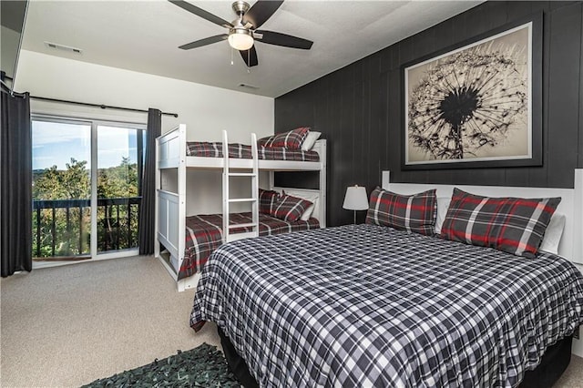 bedroom with carpet floors, wooden walls, visible vents, and a ceiling fan