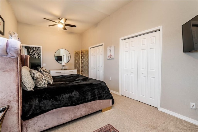 carpeted bedroom with ceiling fan, two closets, and baseboards