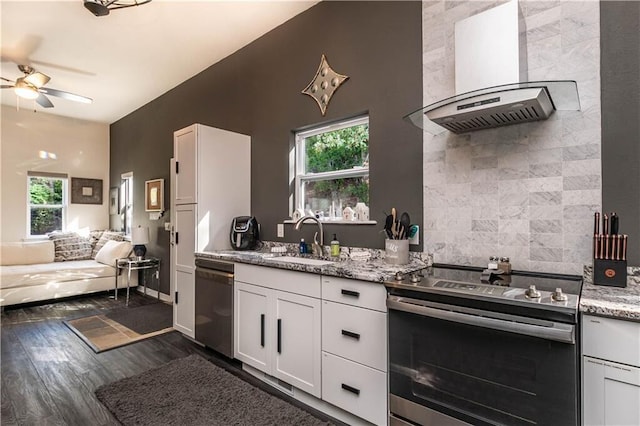 kitchen with open floor plan, wall chimney exhaust hood, appliances with stainless steel finishes, and white cabinets