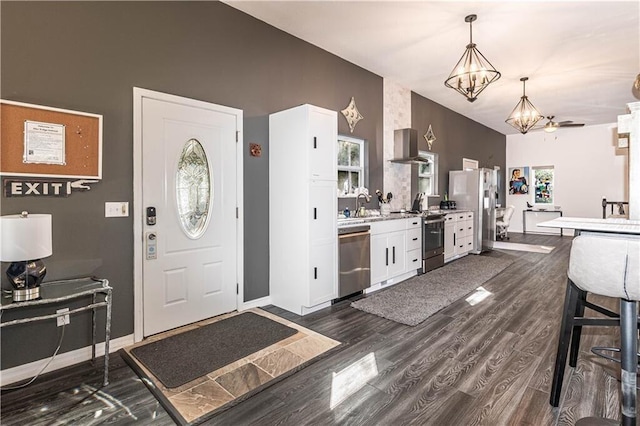 kitchen with dark wood finished floors, a notable chandelier, stainless steel appliances, white cabinetry, and a sink