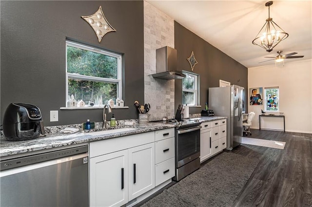 kitchen featuring stainless steel appliances, dark wood-style flooring, a sink, light stone countertops, and wall chimney exhaust hood