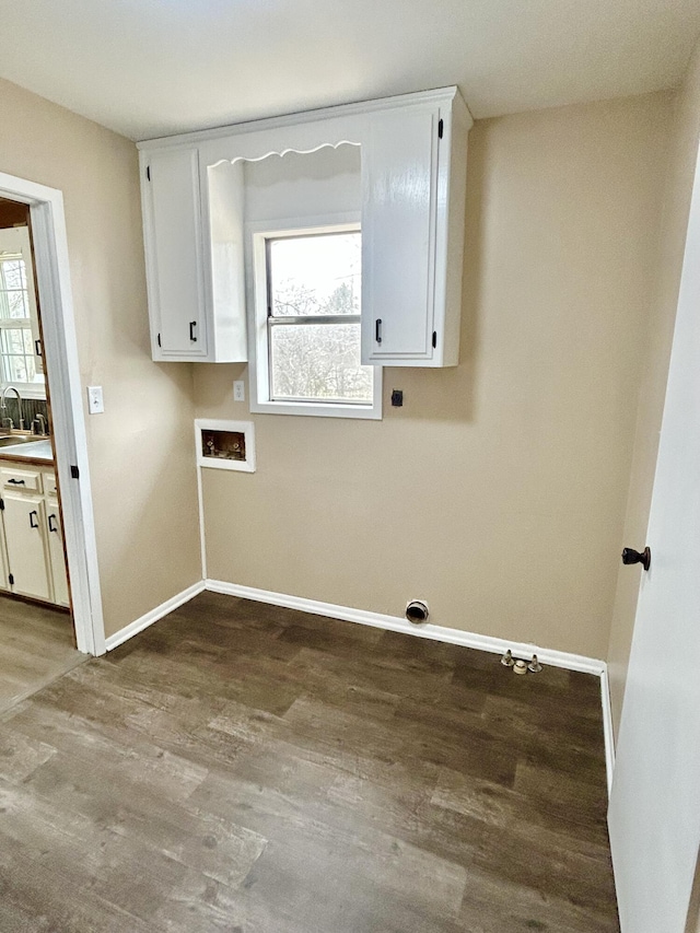 laundry room with hookup for a washing machine, cabinet space, baseboards, and wood finished floors