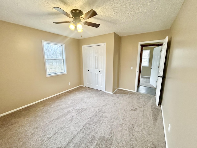 unfurnished bedroom with ceiling fan, a textured ceiling, baseboards, a closet, and carpet