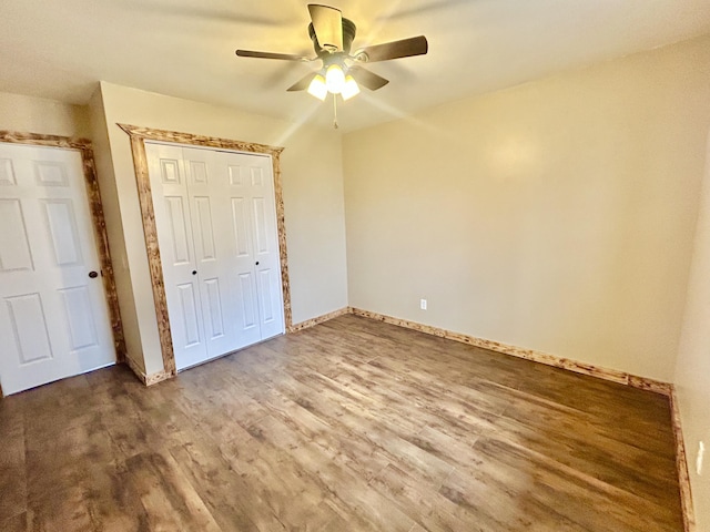 unfurnished bedroom featuring a ceiling fan, a closet, baseboards, and wood finished floors