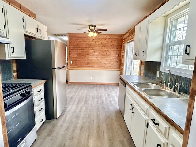 kitchen with light wood-style flooring, gas stove, white cabinets, a sink, and dishwasher