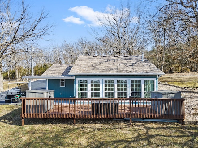 back of house featuring a jacuzzi, roof with shingles, a lawn, and a wooden deck