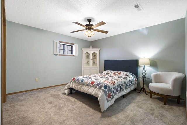 carpeted bedroom with a ceiling fan, baseboards, visible vents, and a textured ceiling