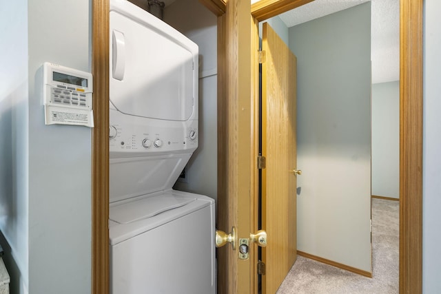 laundry area with stacked washer and dryer, carpet, laundry area, and baseboards