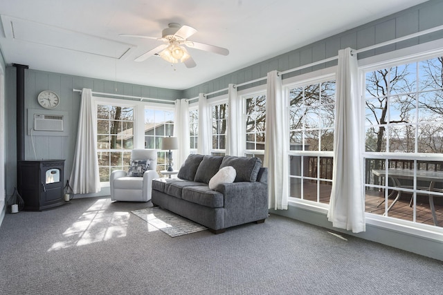 unfurnished sunroom with a wood stove, plenty of natural light, a wall unit AC, and ceiling fan