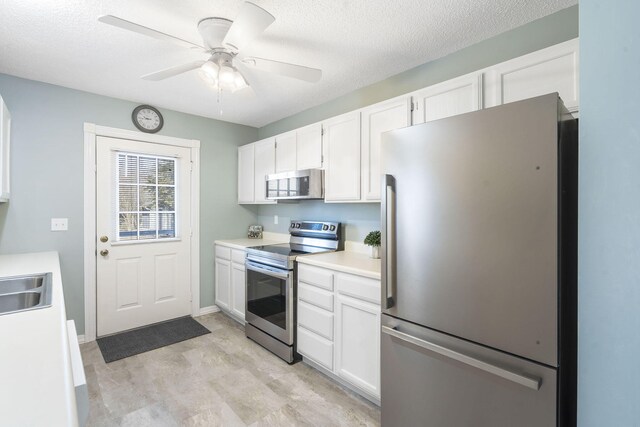 kitchen featuring a textured ceiling, a ceiling fan, white cabinets, light countertops, and appliances with stainless steel finishes