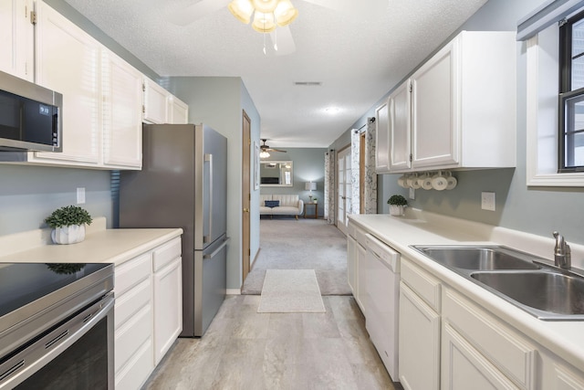 kitchen with appliances with stainless steel finishes, light countertops, white cabinets, and a sink