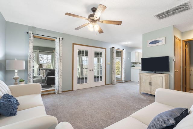 living room with light carpet, ceiling fan, visible vents, and french doors