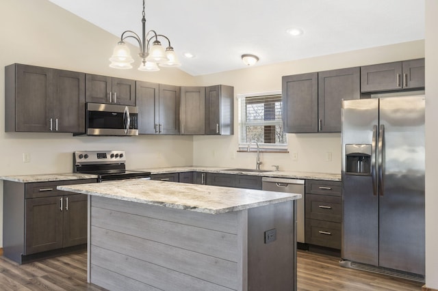 kitchen with a center island, dark wood finished floors, stainless steel appliances, vaulted ceiling, and a sink