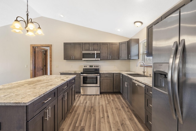 kitchen featuring lofted ceiling, appliances with stainless steel finishes, a sink, dark brown cabinets, and light wood-type flooring