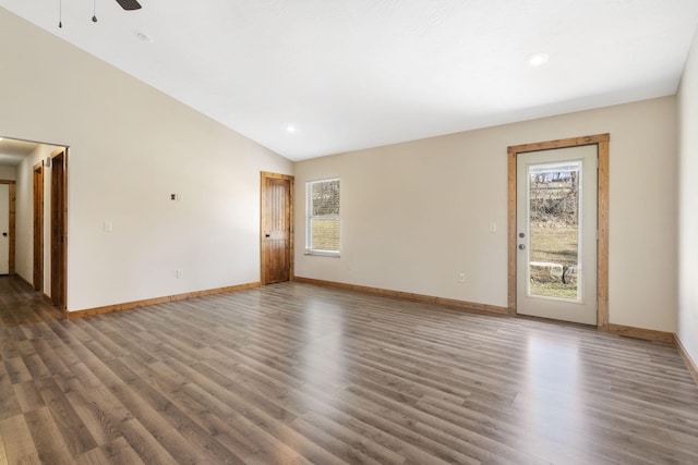 empty room with a wealth of natural light, lofted ceiling, baseboards, and wood finished floors