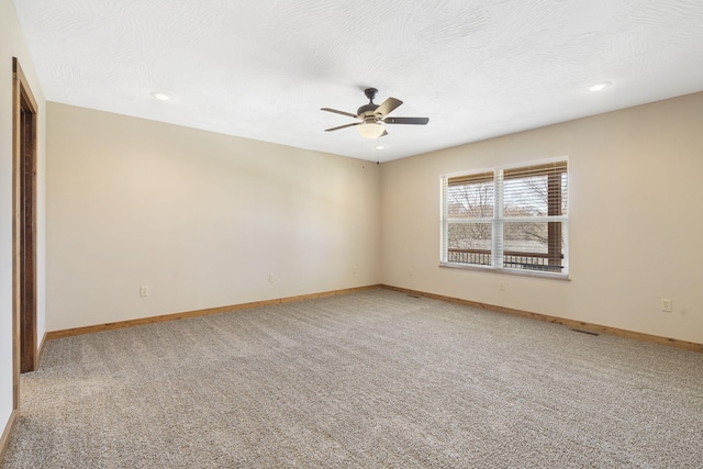 unfurnished room featuring a textured ceiling, light colored carpet, visible vents, baseboards, and a ceiling fan