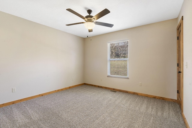 spare room featuring a ceiling fan, light colored carpet, and baseboards