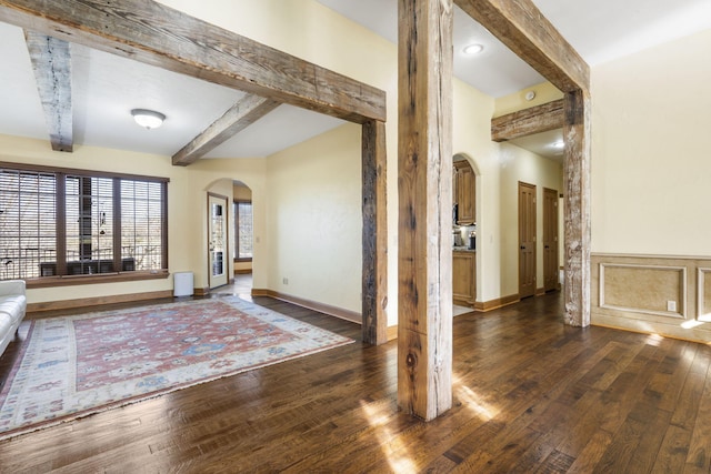 entrance foyer with arched walkways, beamed ceiling, hardwood / wood-style flooring, and baseboards