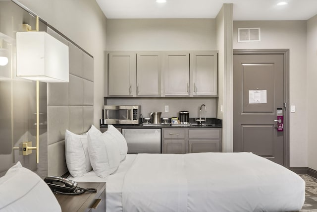 kitchen featuring visible vents, dark countertops, appliances with stainless steel finishes, gray cabinetry, and a sink