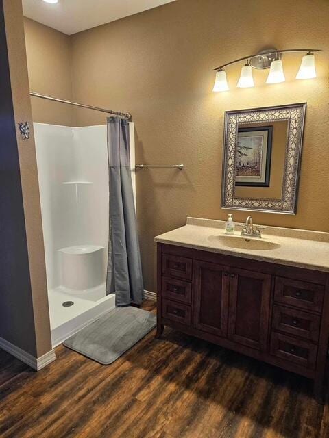 full bathroom featuring a shower with curtain, vanity, baseboards, and wood finished floors